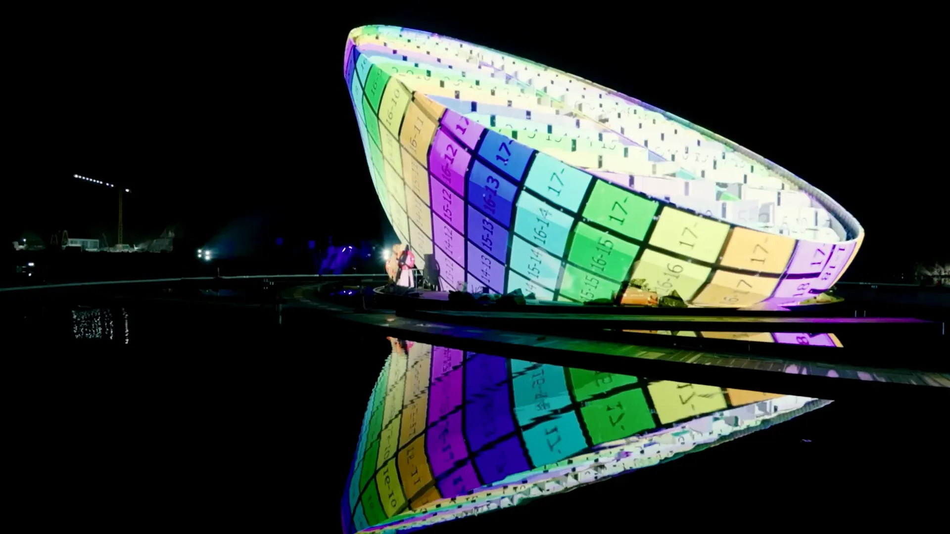 A bowl-shaped structure mapped in colour and numbered cell by cell, reflected in the water